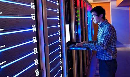 Photo of man standing in front of a bank of servers