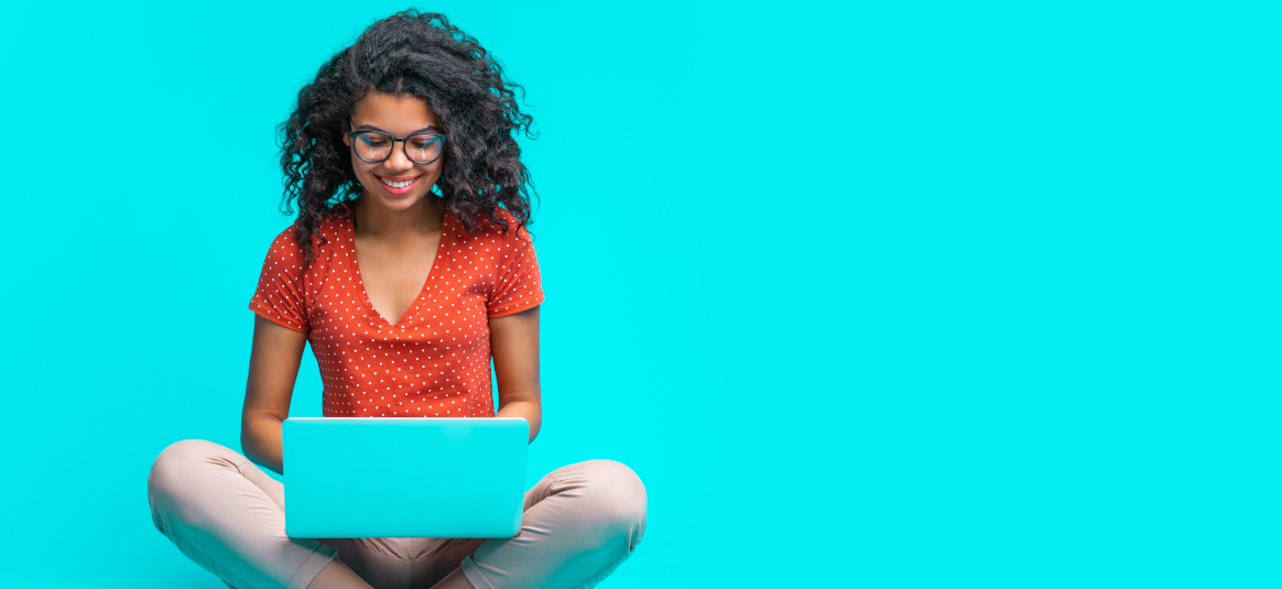 Photo of a smiling woman sitting cross legged with a laptop