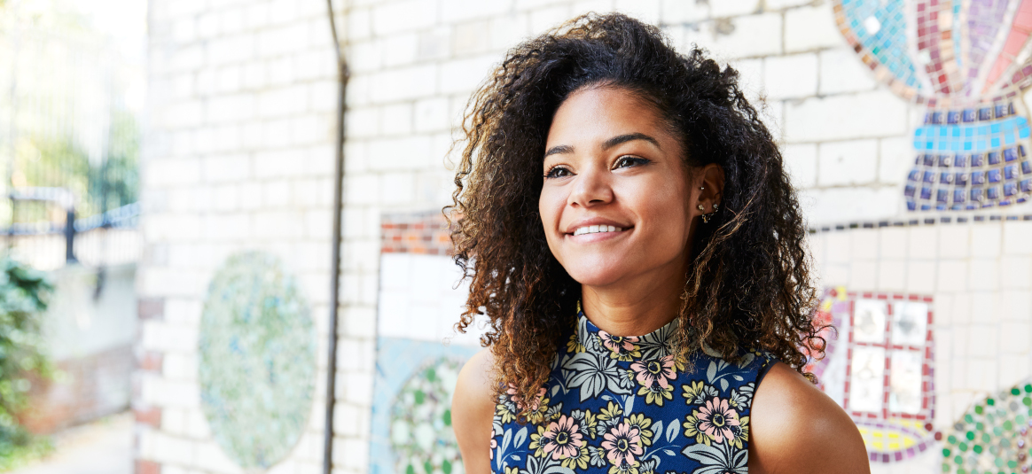 Photo of a smiling woman in front of a mosaic wall