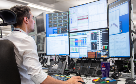 Photo of an office worker at a desk with four monitors